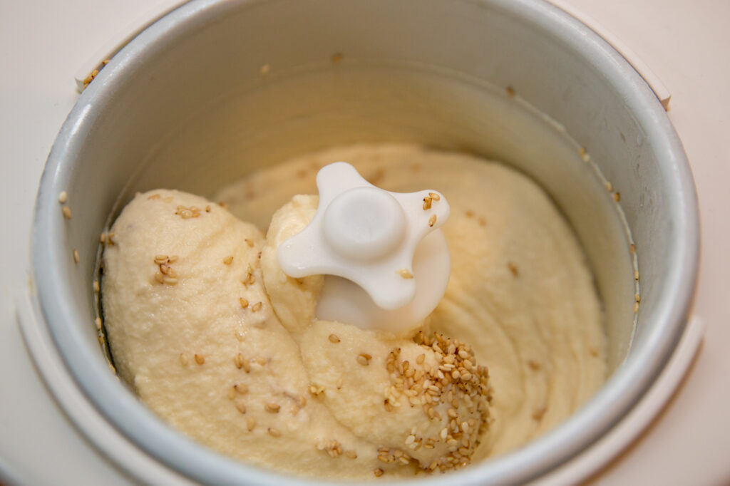 Honey sesame ice cream in the ice cream maker shortly after adding the sesame seeds.