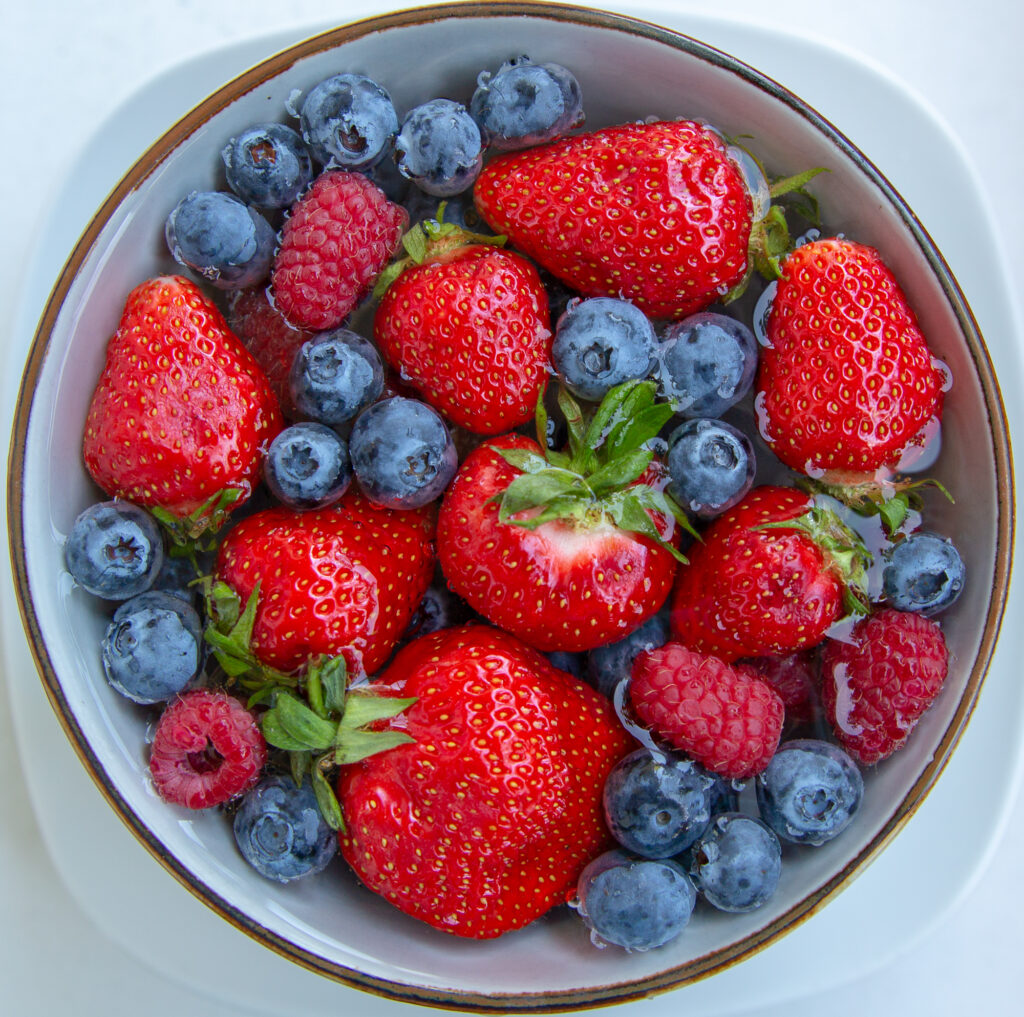 Erdbeeren, Heidelbeeren und Himbeeren beim Waschen