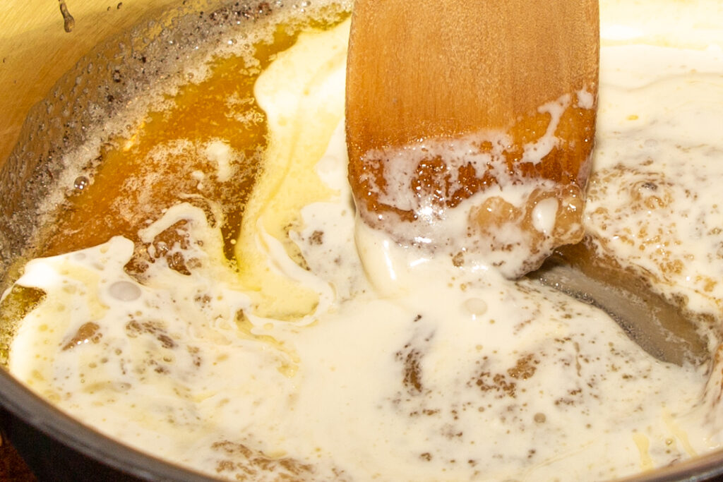 The cream is stirred in sips with a wooden spoon.