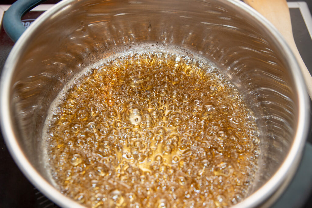 Köchelnden Zuckermasse mit goldbrauner Färbung.