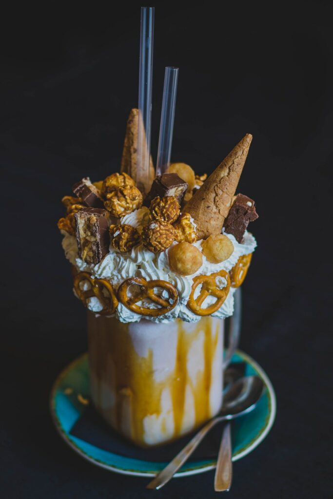 Overflowing ice-cream sundae with lots of decoration made of waffles, pretzels, nuts and cream.