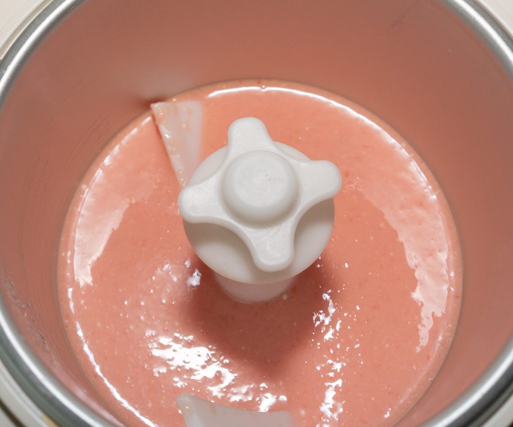 Watermelon-buttermilk ice cream mass in the ice cream machine at the beginning of freezing