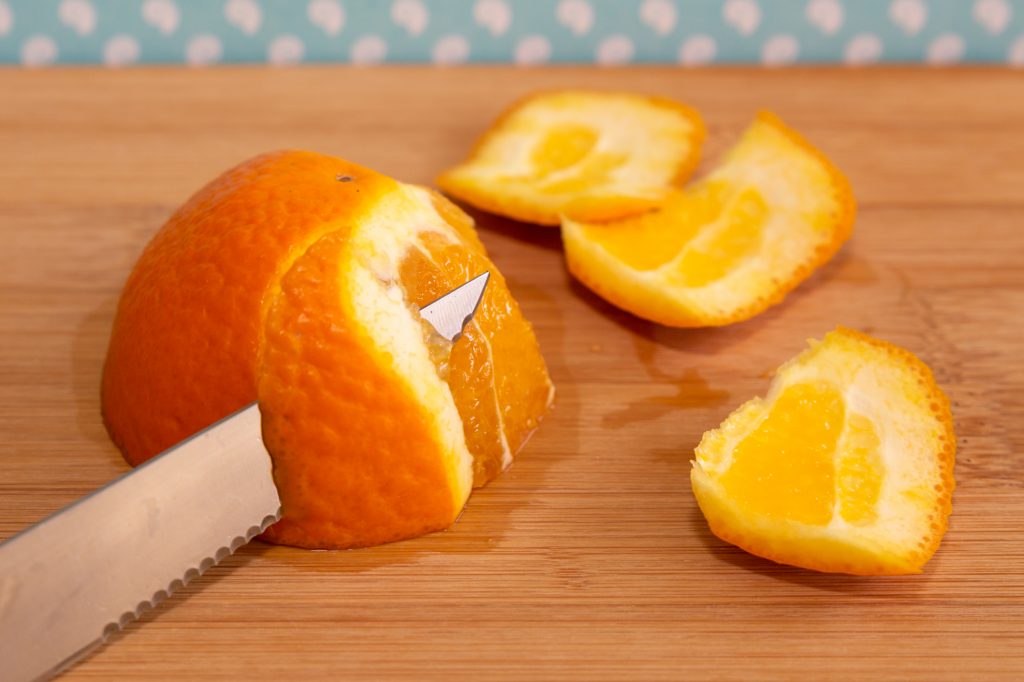 Partir la naranja por la mitad y cortar la piel en tiras, incluida la piel blanca.