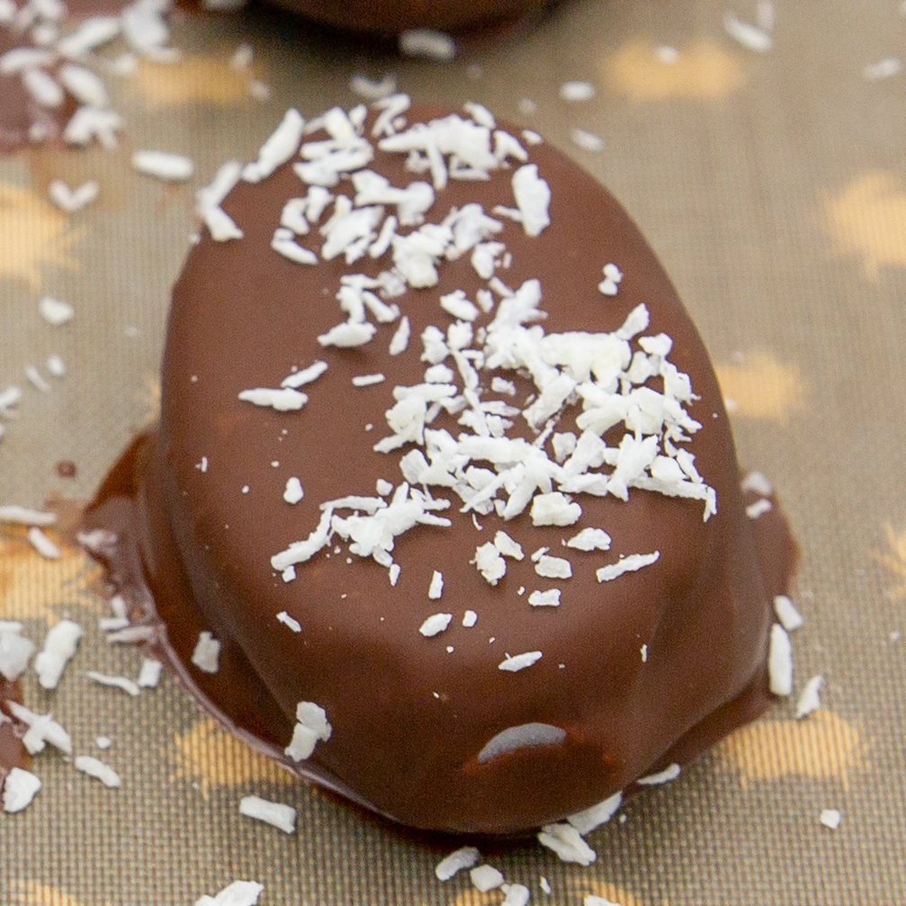 Das selbst gemachte Kokosjoghurt-Eiskonfekt frisch mit Schokolade überzogen. Auf dem Backpapier kurz fest werden lassen und dann zurück ins Gefrierfach.
