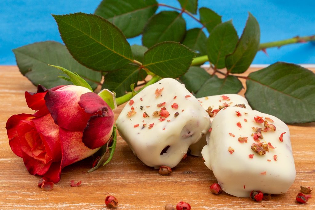 Heidelbeer-Eis Veganes Heidelbeer-Eis als Eiskonfekt mit weißer Schokolade überzogen und rosa Pfeffer bestreut.