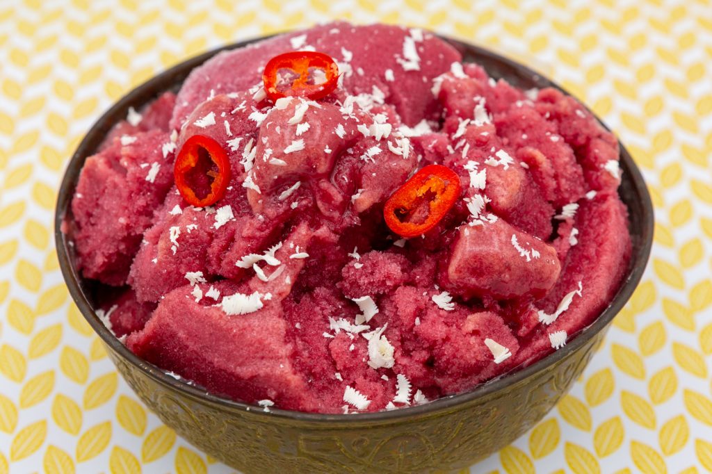 Kirsch-Eis mit feiner Chili-Note und dekoriert mit weißen Schokoraspel. Die Chili ist hier nur zur Dekoration, außer natürlich jemand verträgt so viel Schärfe.