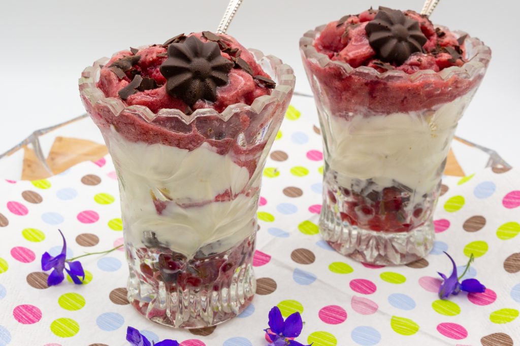 Hier der fertige Eisbecher aus Joghurt- und Kirsch-Eis dekoriert mit Schokoraspel und Schokoladenblüte.