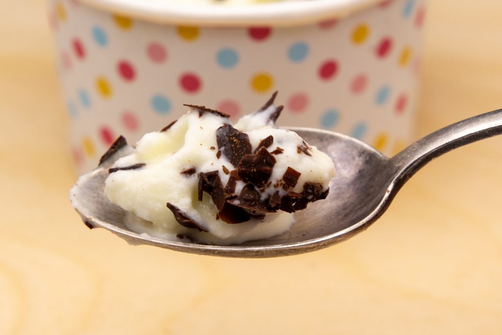 A spoonful of delicious marzipan ice cream with lots of chocolate chips.