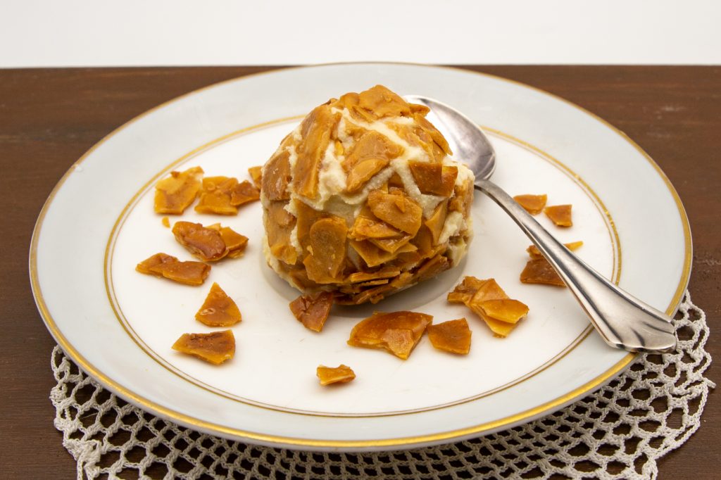 Eine Kugel Bienenstich-Eis umhüllt mit Mandelkrokant.