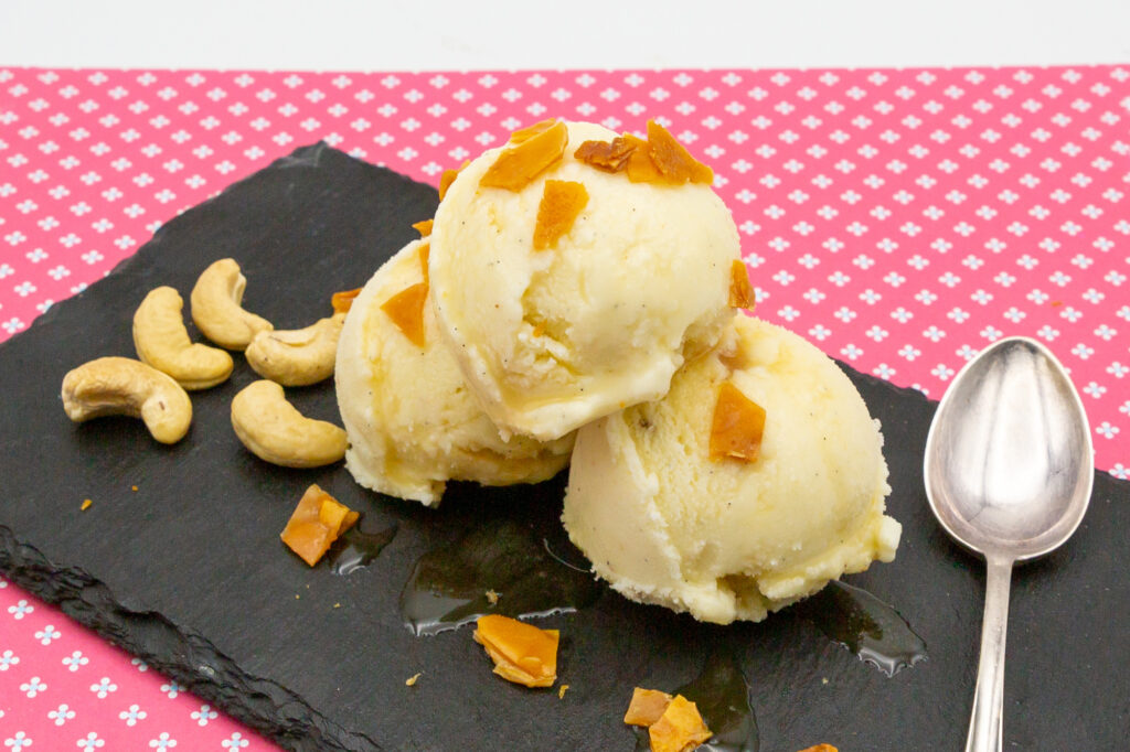 Leckeres Cashew-Eis mit karamellisierten Nüssen und Ahornsirup angerichtet.