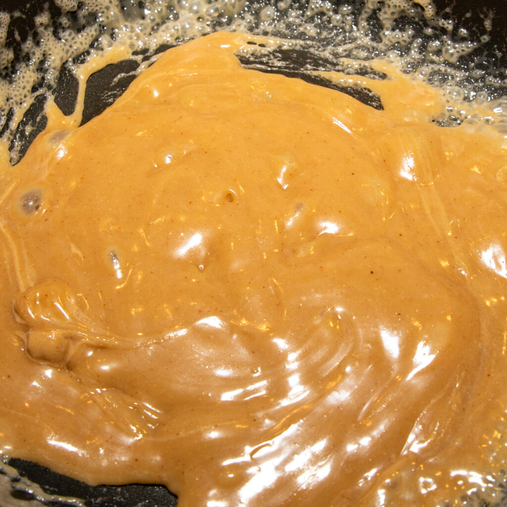 Die fertige Erdnuss-Karamell-Sauce sollte noch heiß in ein Gefäß gefüllt werden.