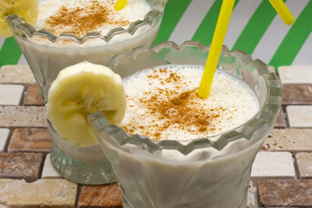 Delicious vegan banana milkshake sprinkled with cinnamon and decorated with banana slice.