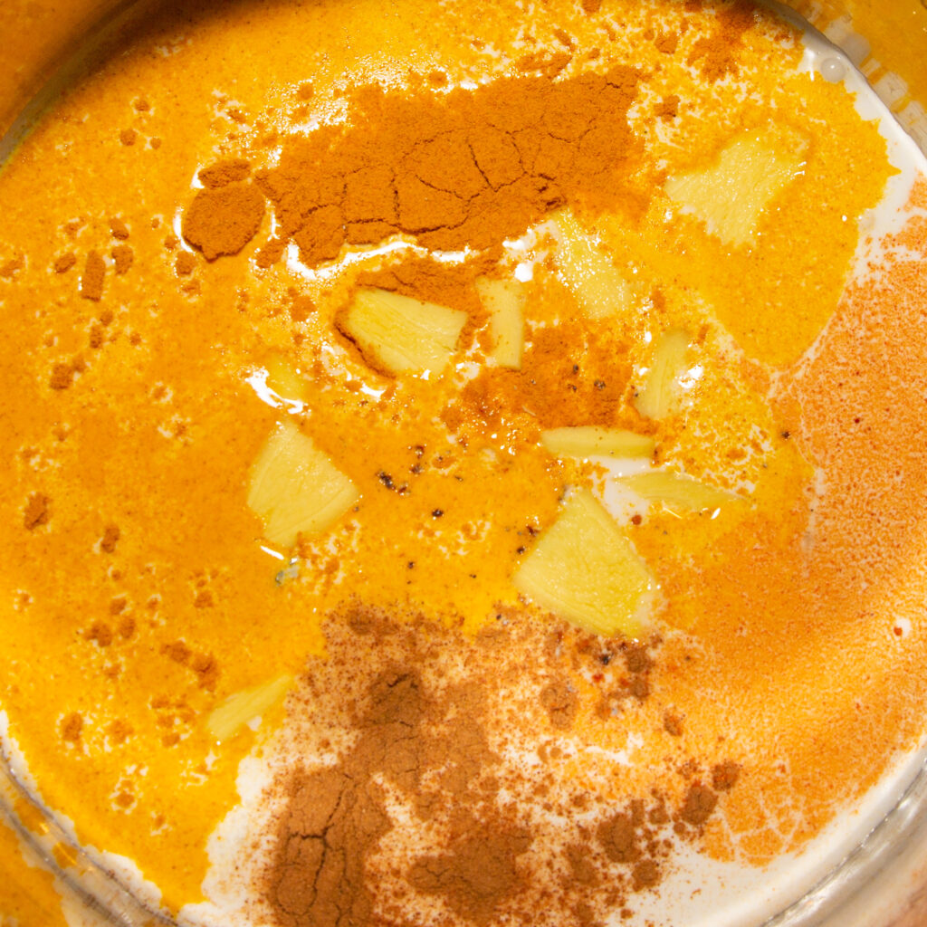 Goldenes Milch-Eis Kokosmilch mit den Gewürzen und Ingwerscheiben als Vorbereitung für die Goldene Milch Eismasse.