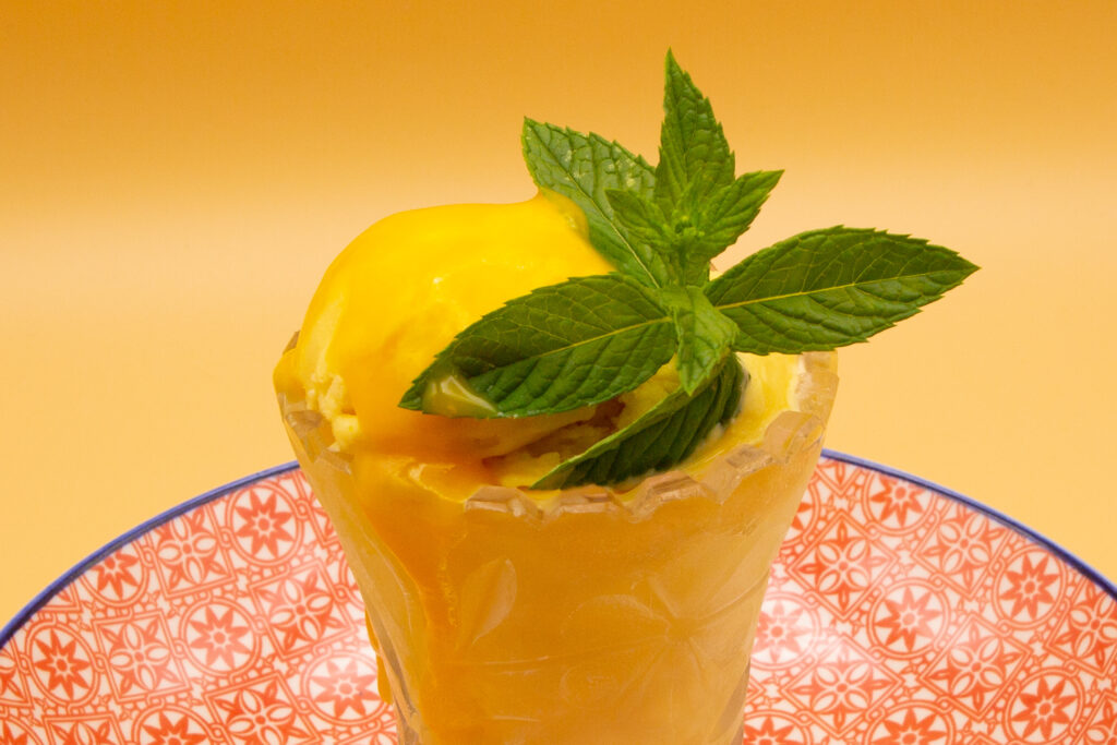 Cremoso helado de mango decorado con menta y puré de mango