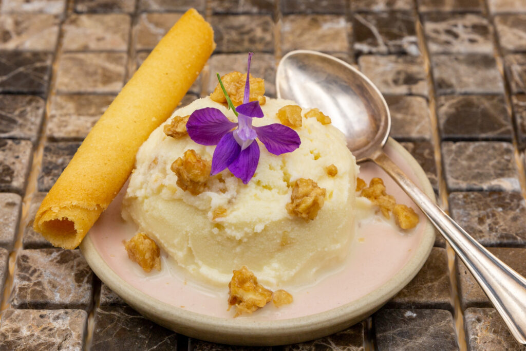 Angerichtetes Walnuss-Eis mit Waffelröhrchen und karamellisierten Walnüssen.