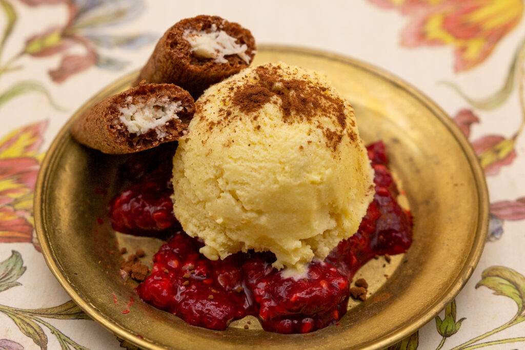 Maracuja-Eis Maracuja-Eis auf Himbeersoße und mit Kakao bestäubt.