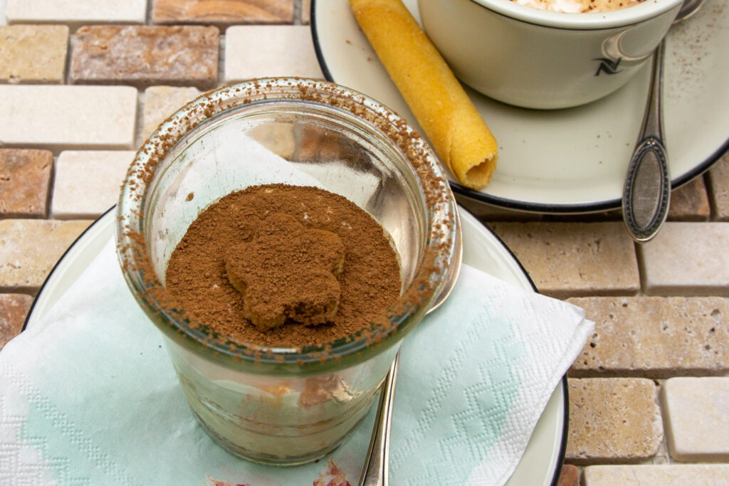 Tiramisu-Eis mit Kakao bestreut und zu einem Cappuccino serviert ist purer Genuss.