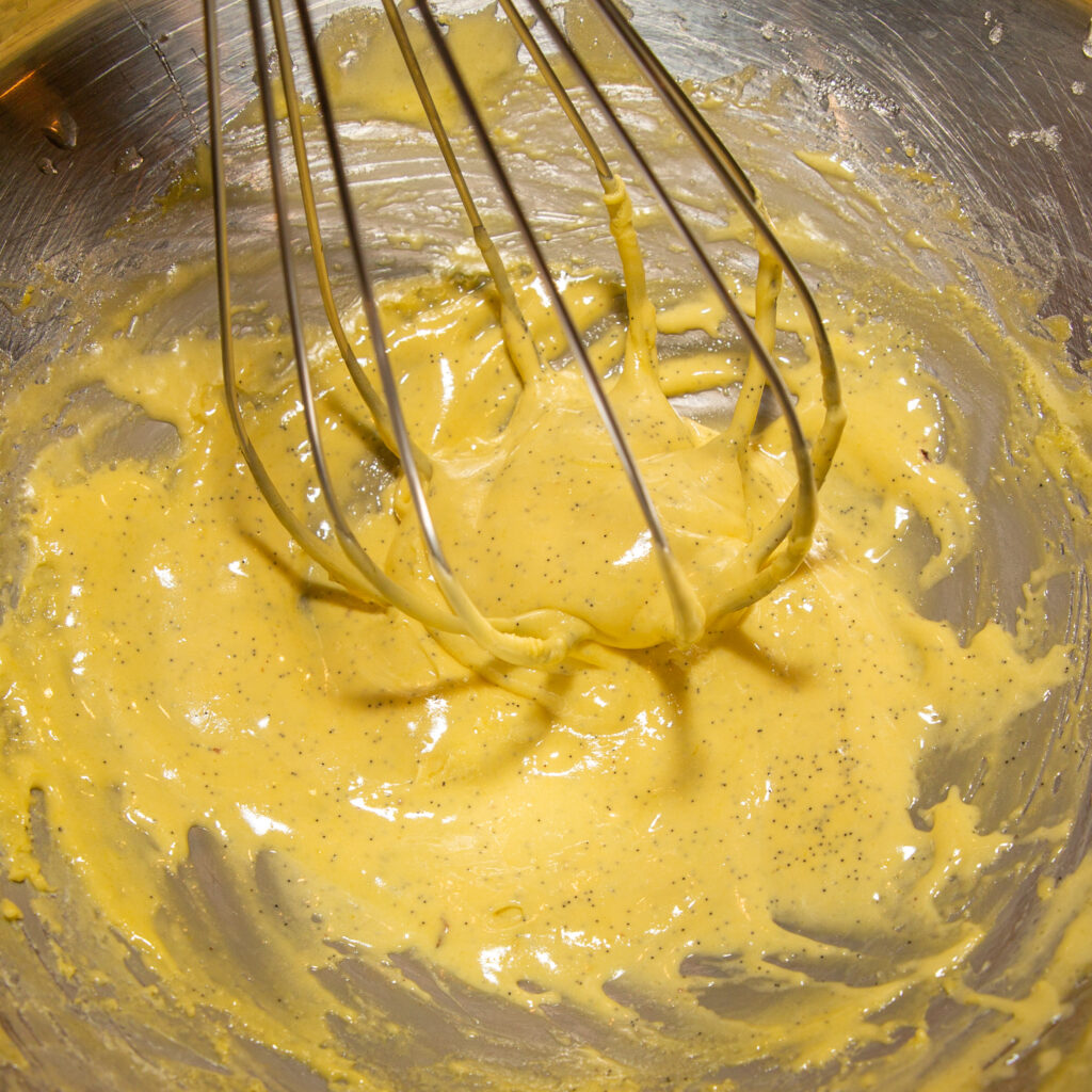 Batir las yemas de huevo, el azúcar y la vaina de vainilla al baño maría hasta obtener una consistencia cremosa.