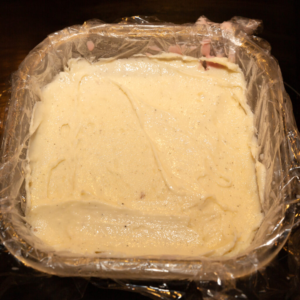The finished vanilla ice cream is poured as a second layer into the square mold on top of the raspberry ice cream and smoothed.