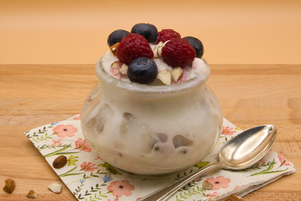 Veganes Vanille-Eis mit Heidelbeeren, Himbeeren und gehackten Mandeln als Topping.