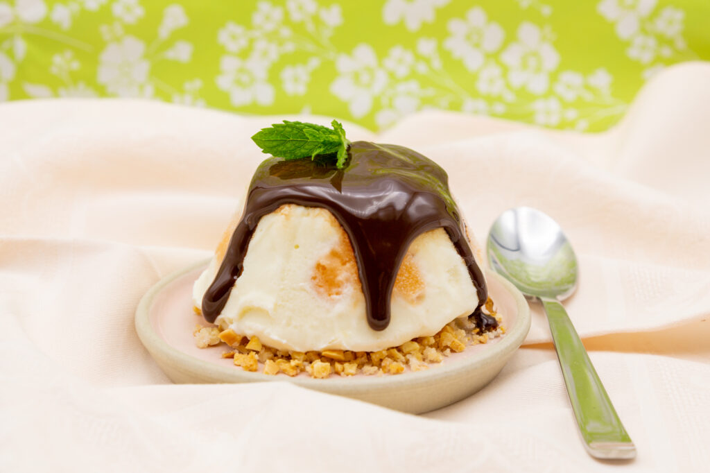 Yogur helado de yogur griego con fruta y salsa de chocolate sobre nueces caramelizadas