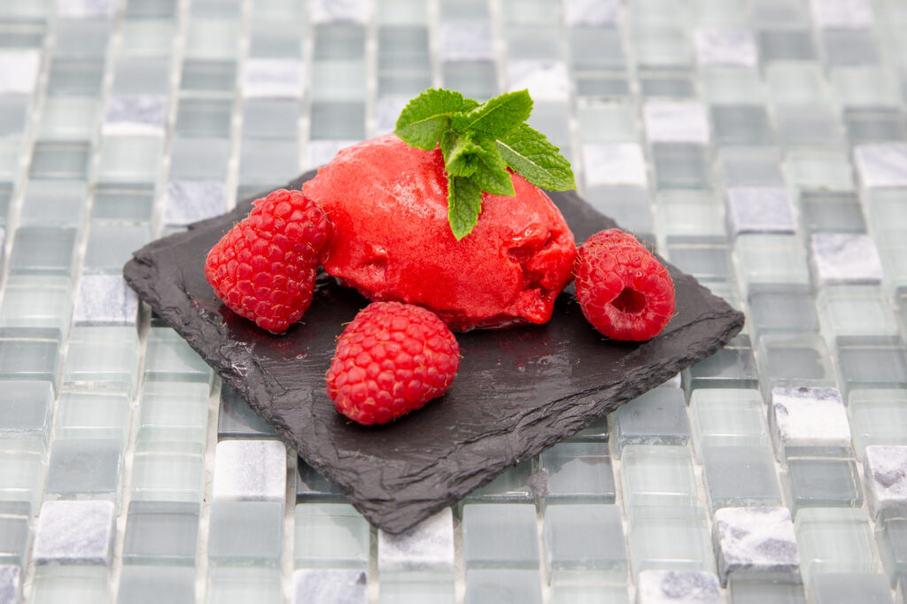 Himbeer-Sorbet Ein leckeres, fruchtiges Himbeer-Sorbet dekoriert mit Minze.